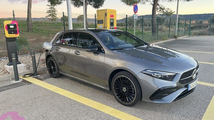 Coche eléctrico de color gris en estación de carga rápida, preparado para recargar energía en un pun.