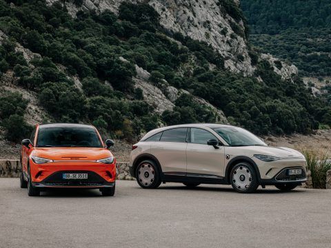 Dos coches eléctricos en un paisaje montañoso con vegetación densa.