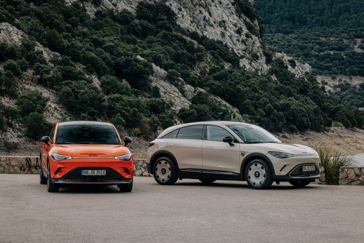 Dos coches eléctricos en un paisaje montañoso con vegetación densa.
