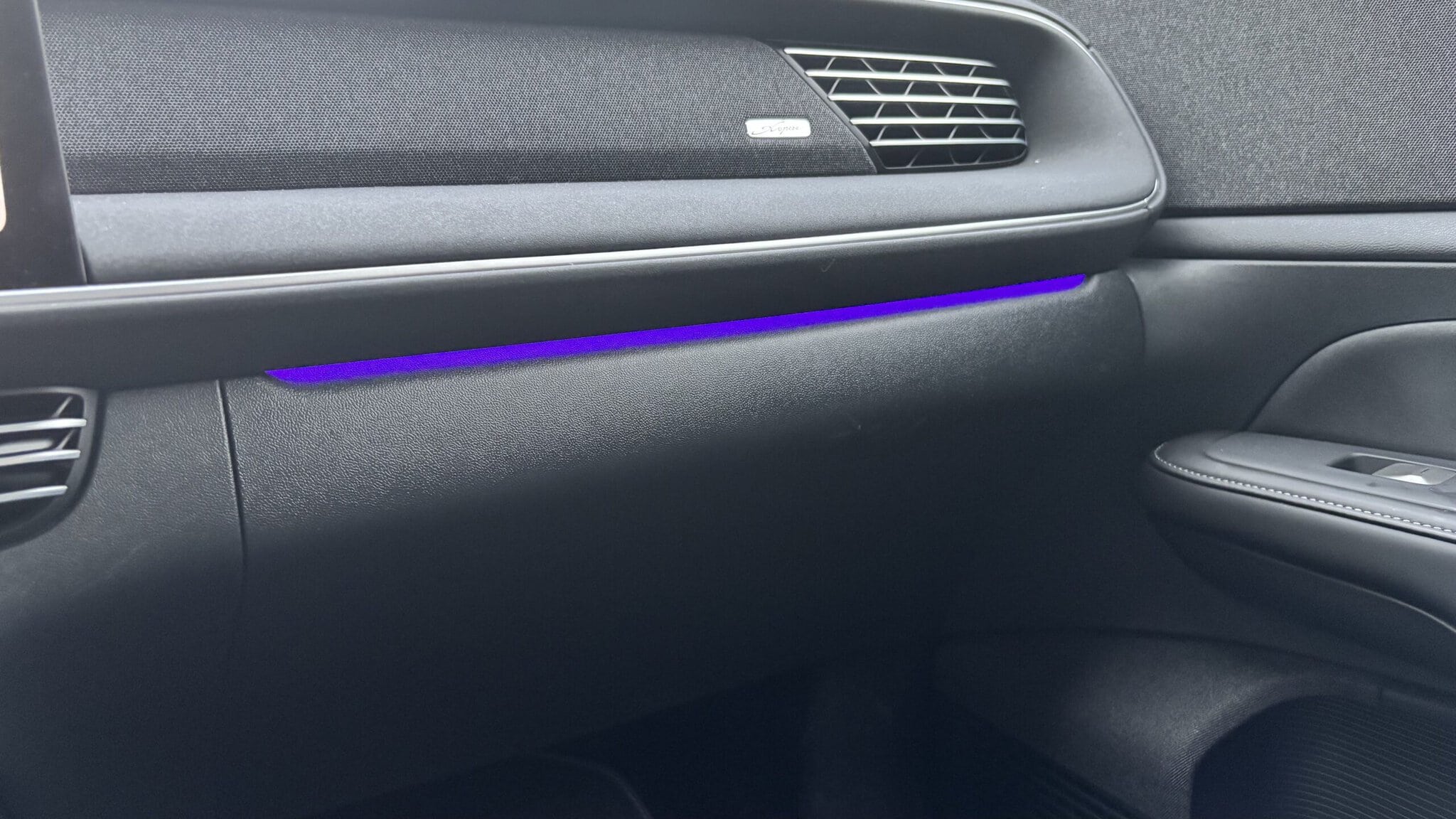 Interior de coche eléctrico con iluminación LED azul en el tablero.