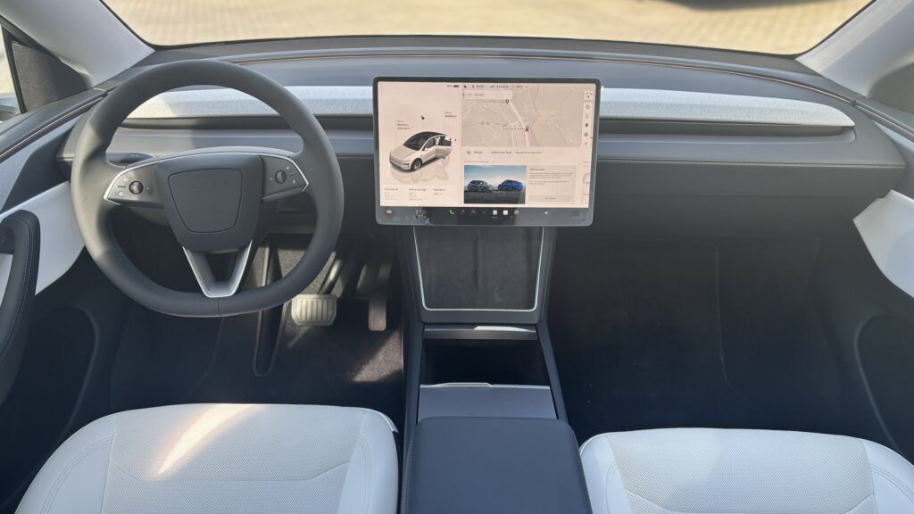 Interior de un coche eléctrico con pantalla táctil central y volante moderno.